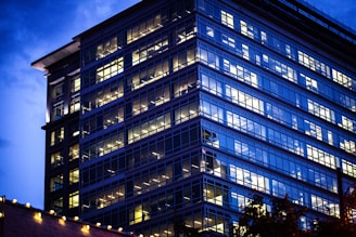 A sleek, modern office building glowing under the Dubai skyline at dusk.