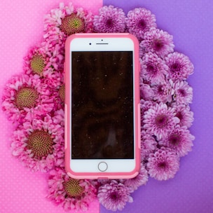 gold iPhone 6 with pink case on white flower background