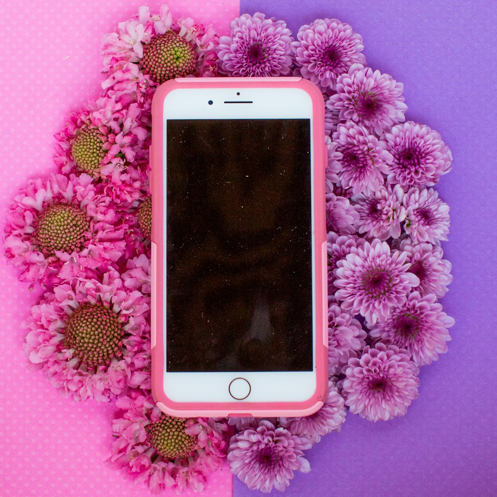 gold iPhone 6 with pink case on white flower background