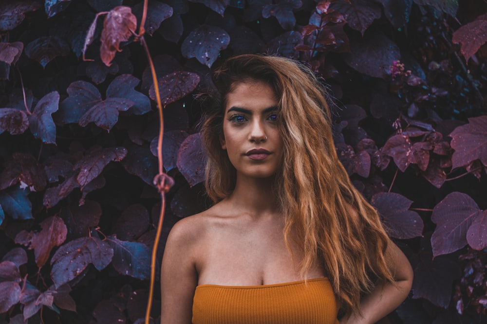 woman in brown strapless top standing in front of plants