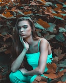 Portrait of Claudia Porcher in warm beige and sage green tones, sitting calmly in nature.