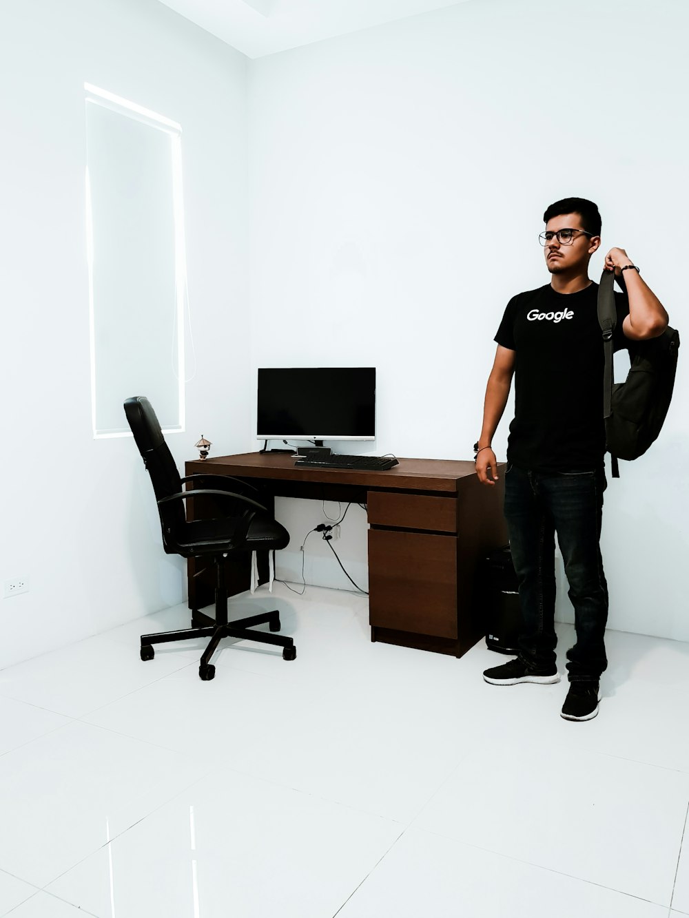 hombre de pie cerca de un escritorio marrón junto a una pared blanca