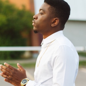 Man wearing a minimalist silver chain against a blurred cityscape background at dusk