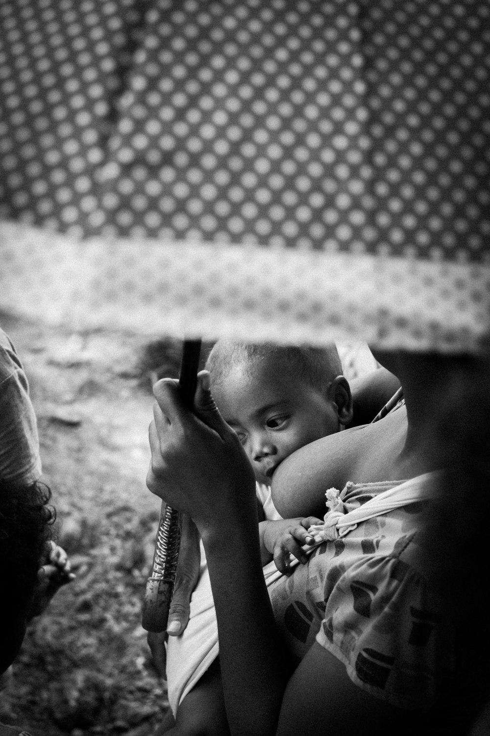 grayscale photo of breastfeeding mother with umbrella