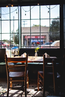 Cozy corner of Yilin's Cafe with sunlight streaming through the window onto a wooden table set for two.
