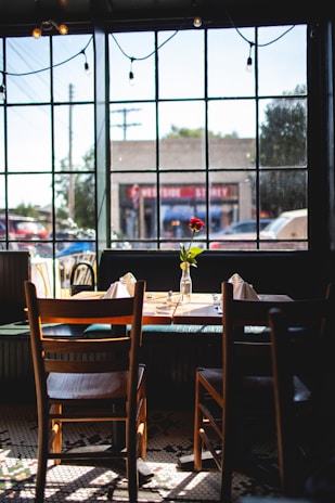 Cozy corner of Yilin's Cafe with sunlight streaming through the window onto a wooden table set for two.