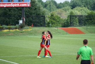 A young athlete celebrating after scoring a goal on a college sports field.