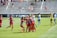 Young boy celebrating a soccer goal with a coach clapping beside him on the field.