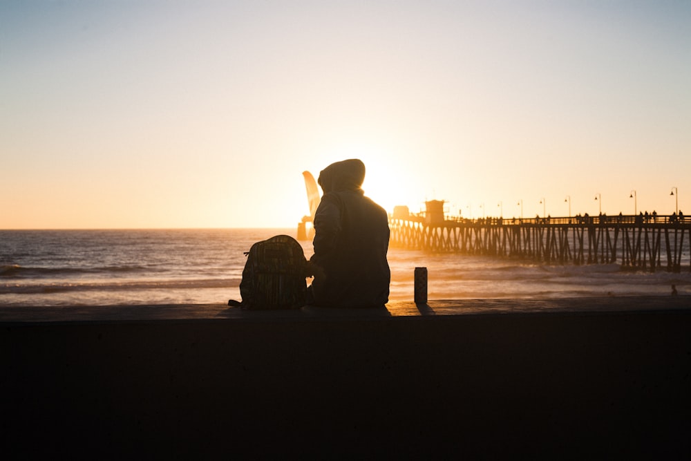 a person sitting on a bench next to the ocean