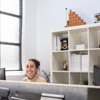 A smiling bilingual paypro support representative answering a phone call in a bright office.