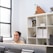 A smiling business owner reviewing positive customer feedback on a laptop in a bright office.