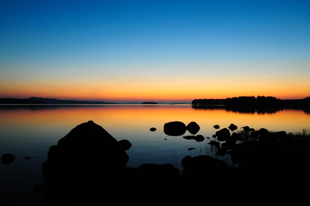 body of water with rock under blue sky during daytime