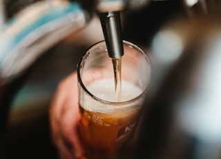 person filling clear glass with liquid