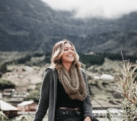 woman sitting beside grass near mountain range