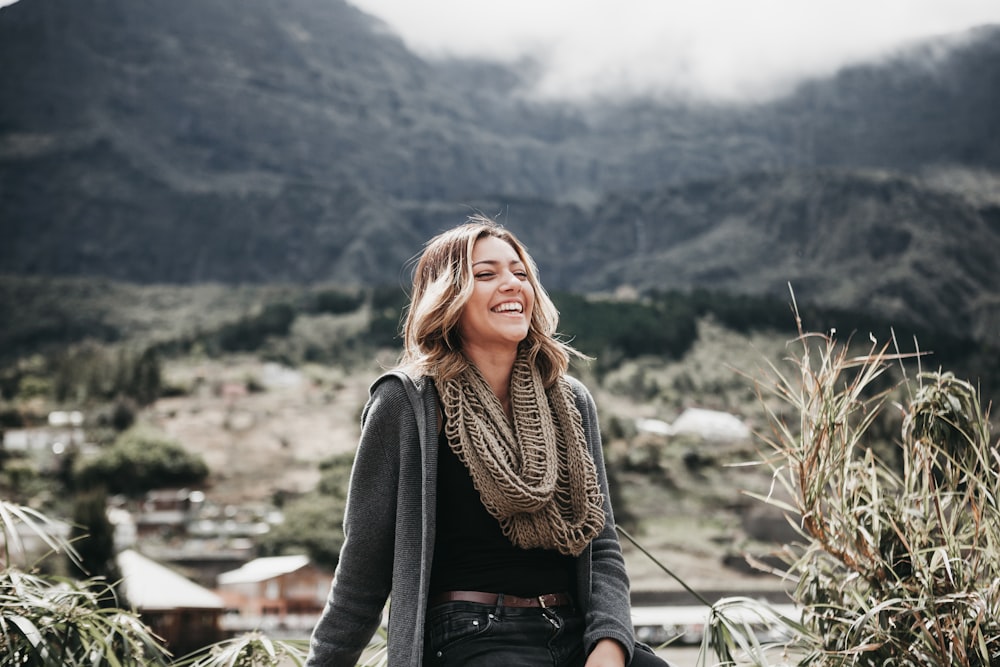 woman sitting beside grass near mountain range