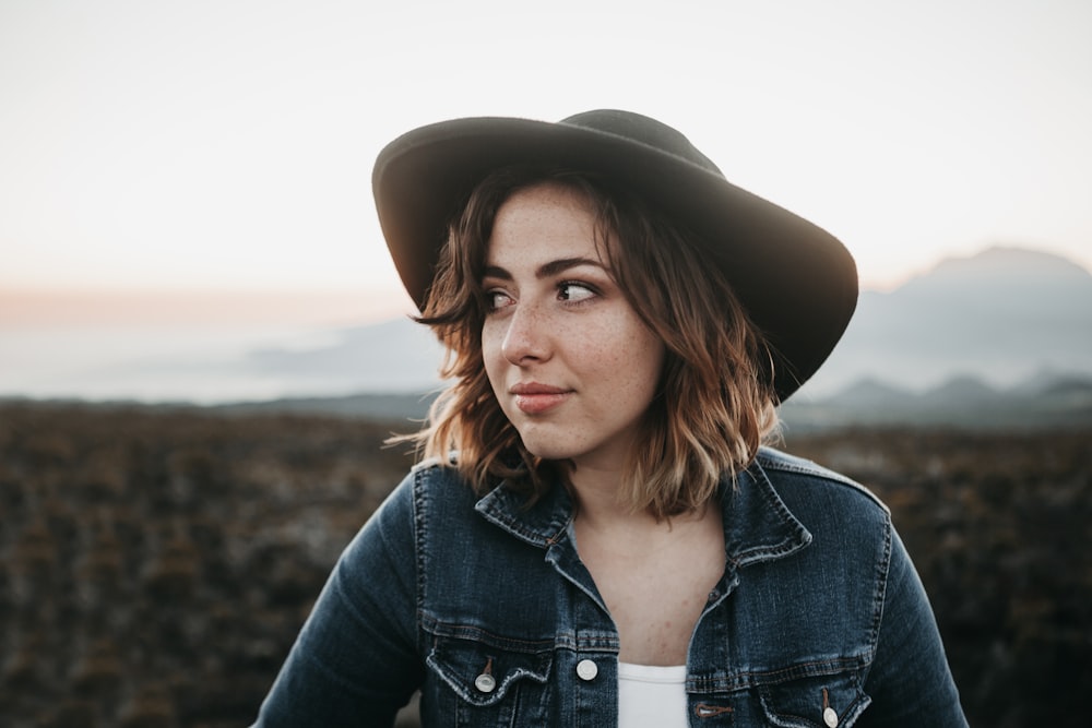 Mujer sonriente con sombrero negro y top de mezclilla azul