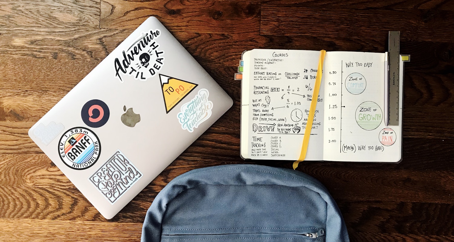 flat lay photography of blue backpack beside book and silver MacBook