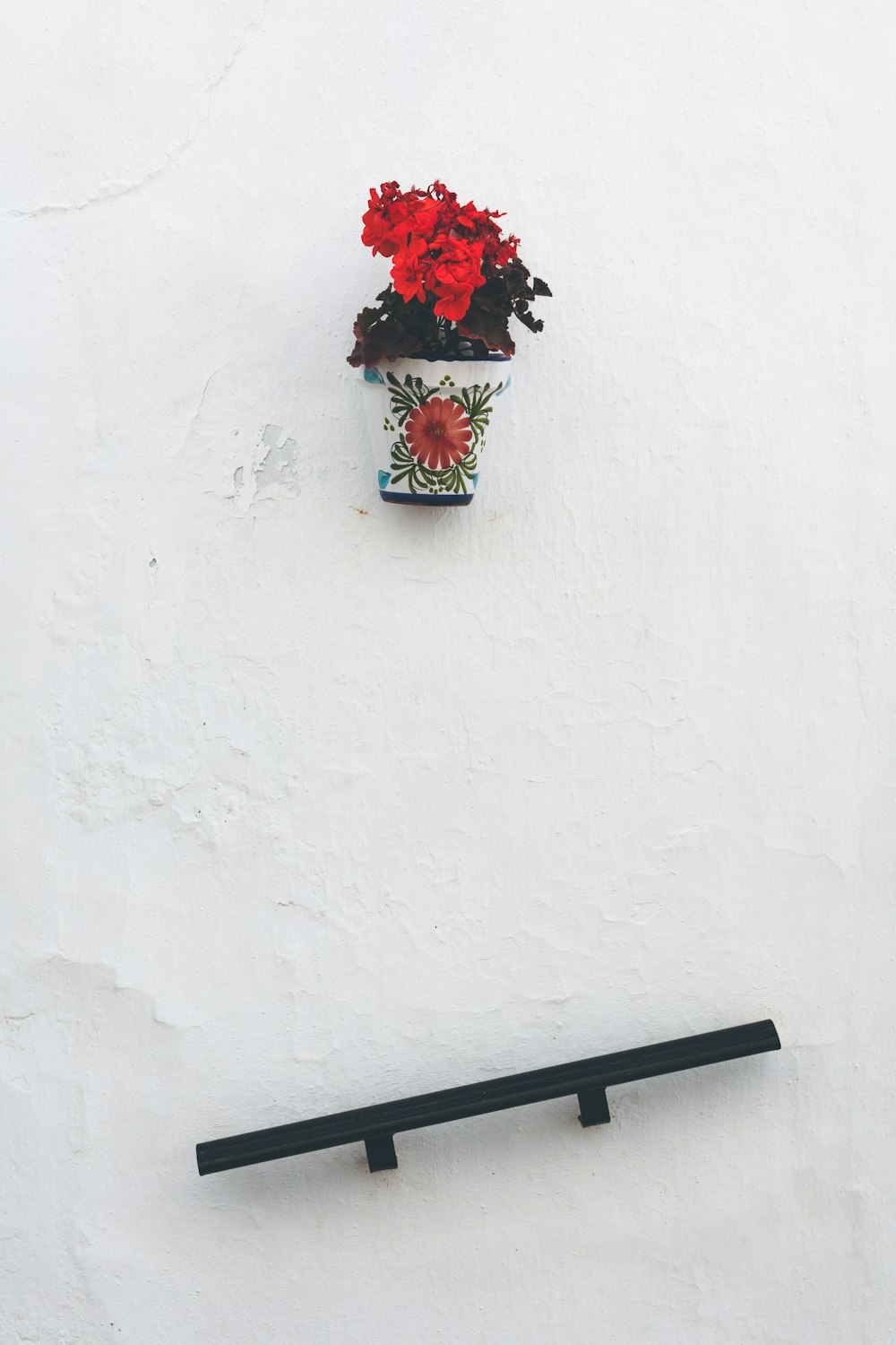 black shelf under red flowers in vase