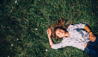 woman lying on grass during daytime