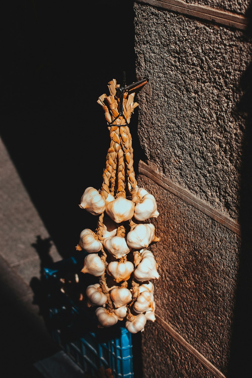 brown garlics hanged on wall at daytime