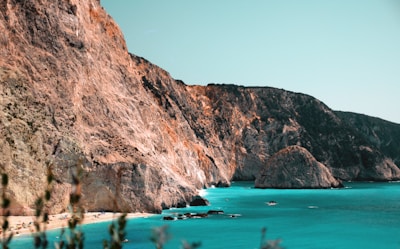 Sunlight sparkling on the crystal-clear waters of Costa Rossa beach with a backdrop of rugged Sardinian cliffs.