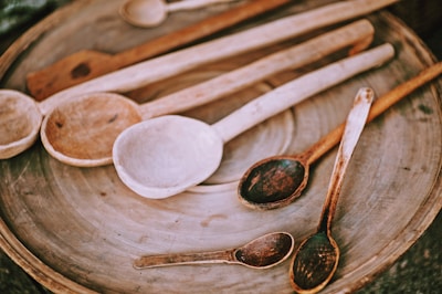 A close-up of handcrafted wooden spoons and spatulas resting on a rustic kitchen counter.