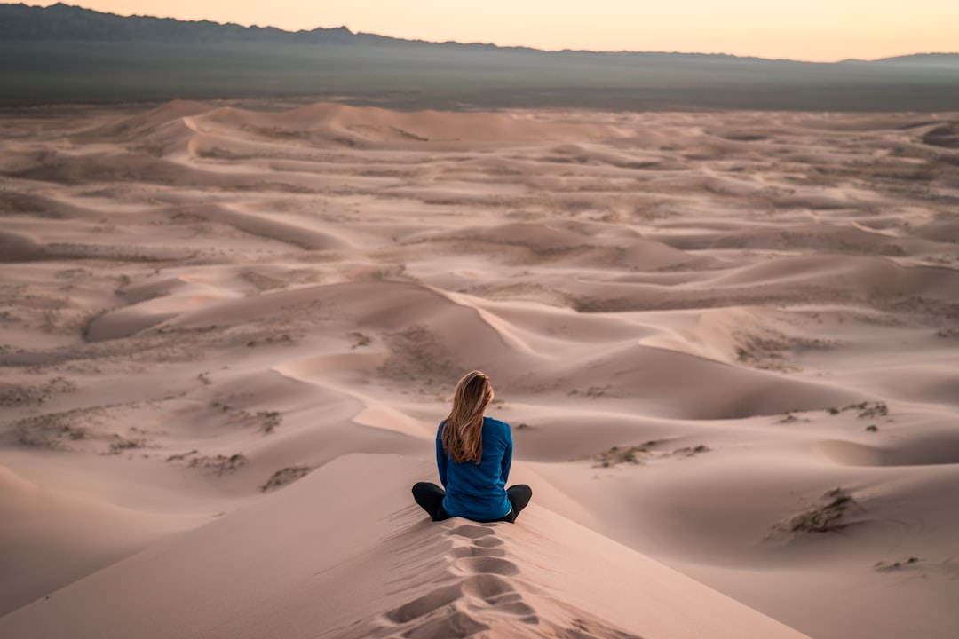 woman sitting on sand field,