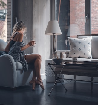 woman sitting on gray sofa chair holding mug