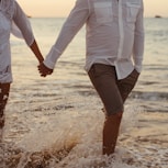 couple holding hands walking on shore