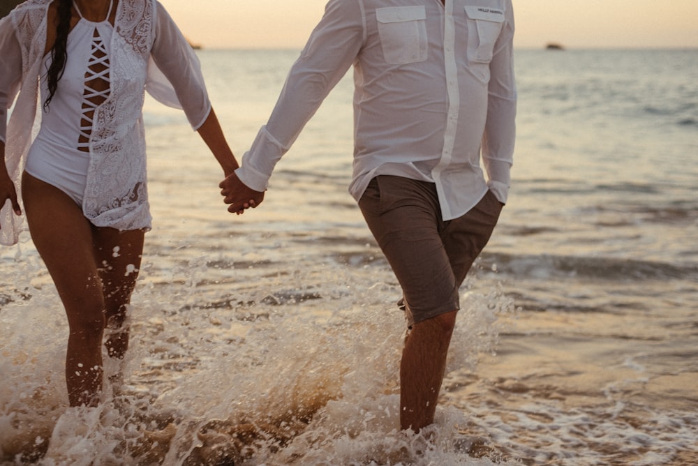 couple holding hands walking on shore