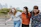three women walking on brown wooden dock near high rise building during daytime