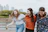 three women walking on brown wooden dock near high rise building during daytime