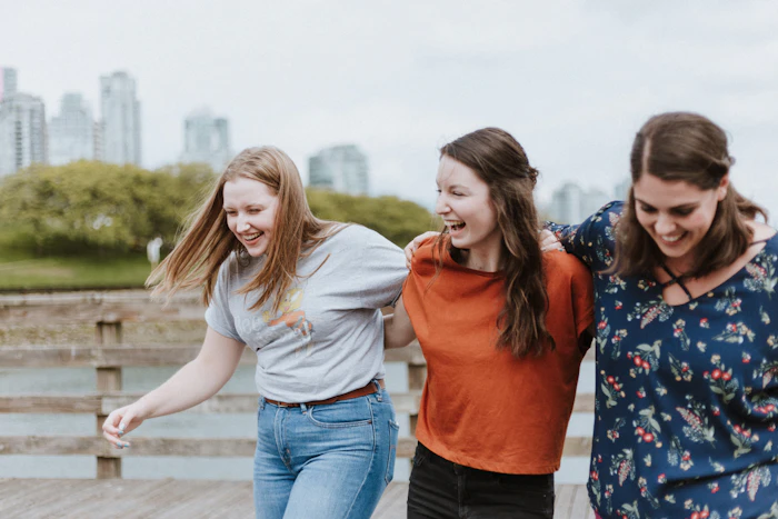 Three friends walking together on a dock, laughing