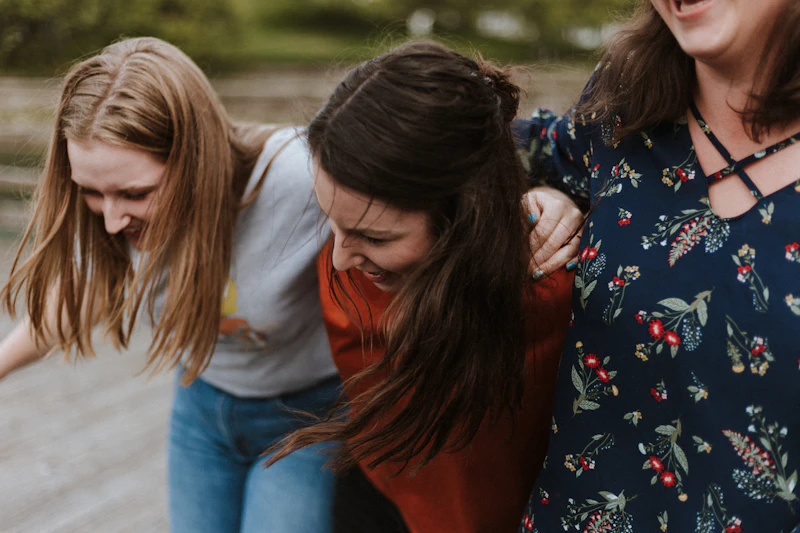 Três mulheres abraçadas, rindo juntas