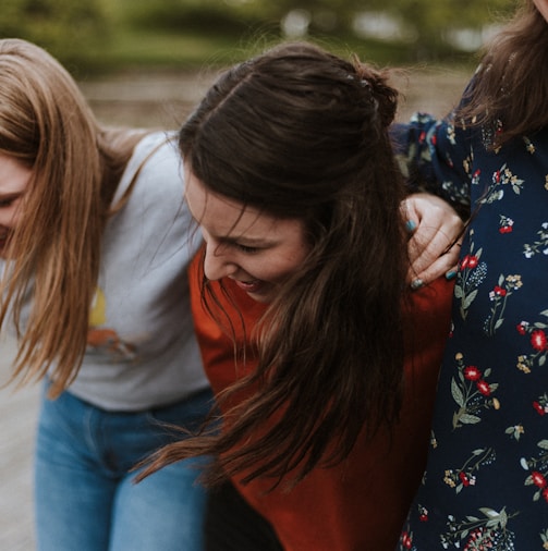 three woman holding each other and smiling while taking a photo