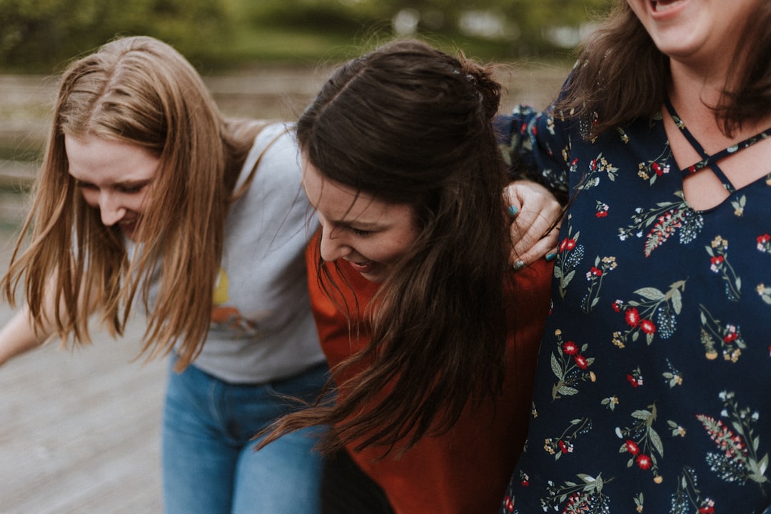 three woman holding each other and smiling while taking a photo,