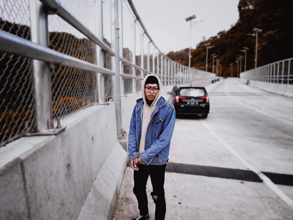 a man standing on the side of a road next to a fence