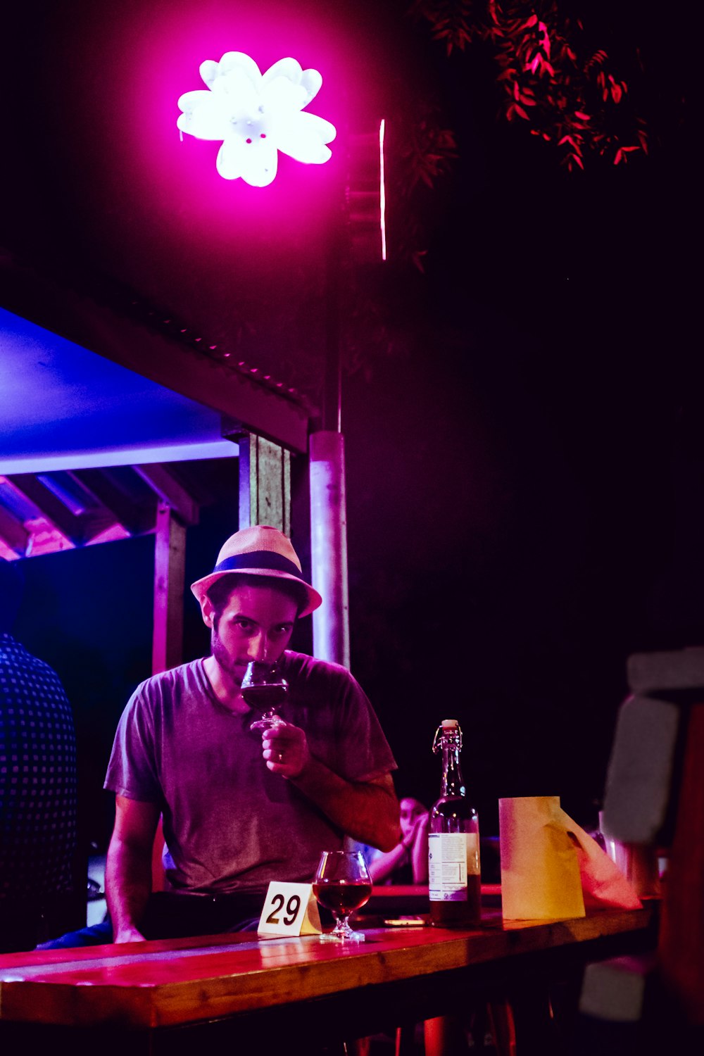 homem vestindo camisa cinza segurando copo de vinho