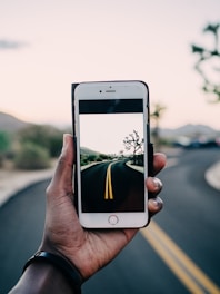 person using gold iPhone 6 capturing road