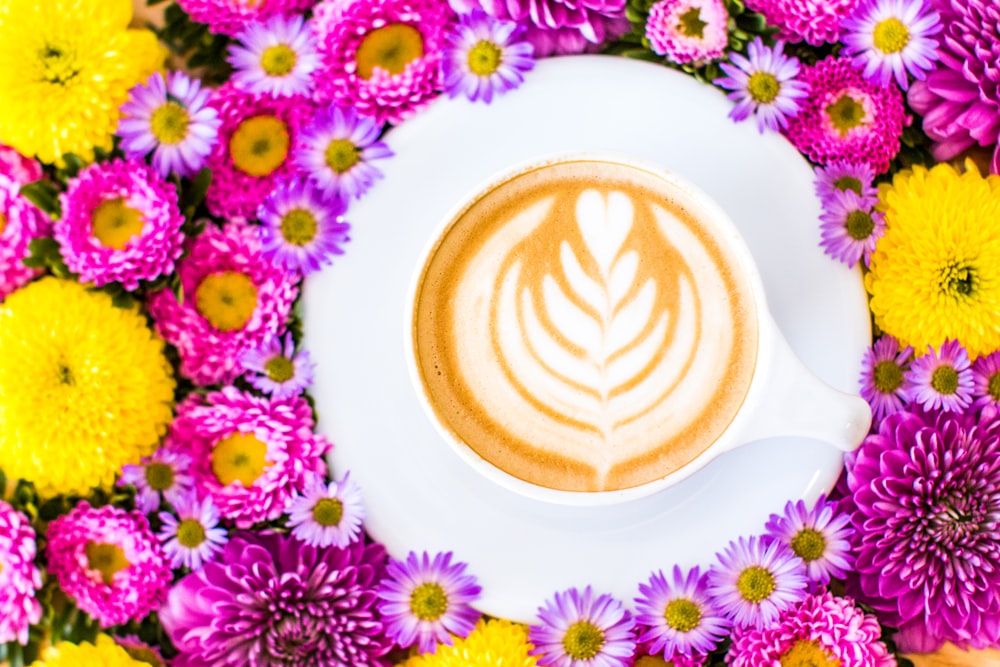 ceramic tea cup on white saucer surrounded by purple flowers