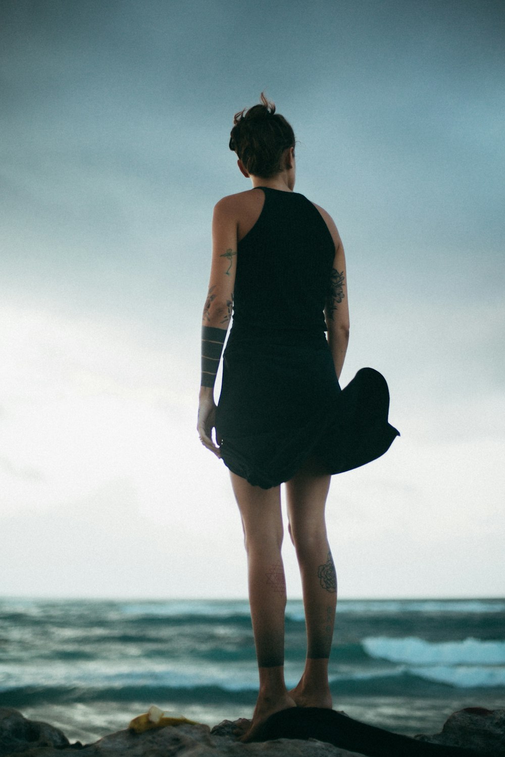 woman standing on rock looking at the sea during daytime