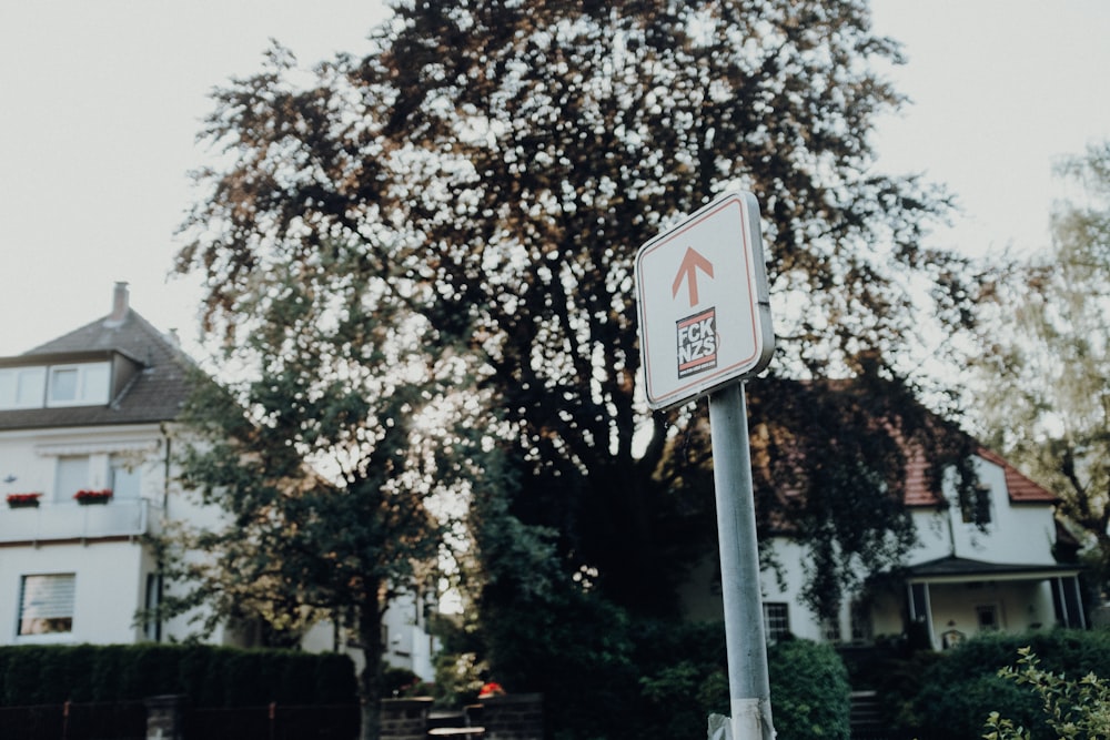 seta para cima sinal de rua perto da árvore