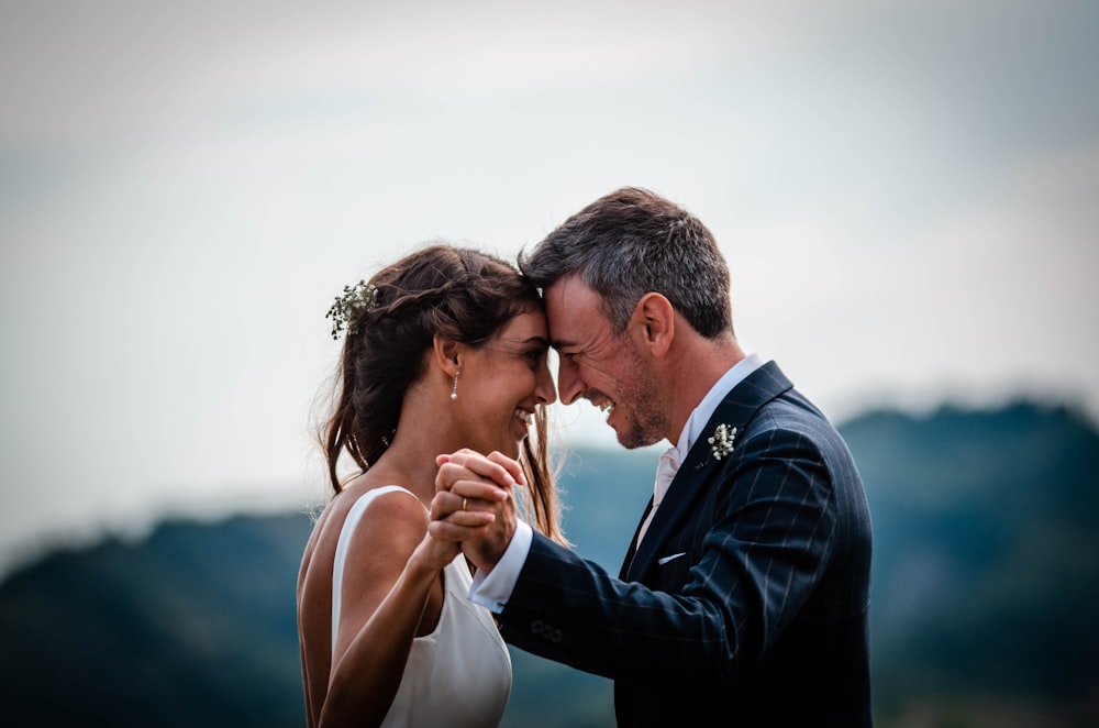 men's black suit jacket and women's white sleeveless gown