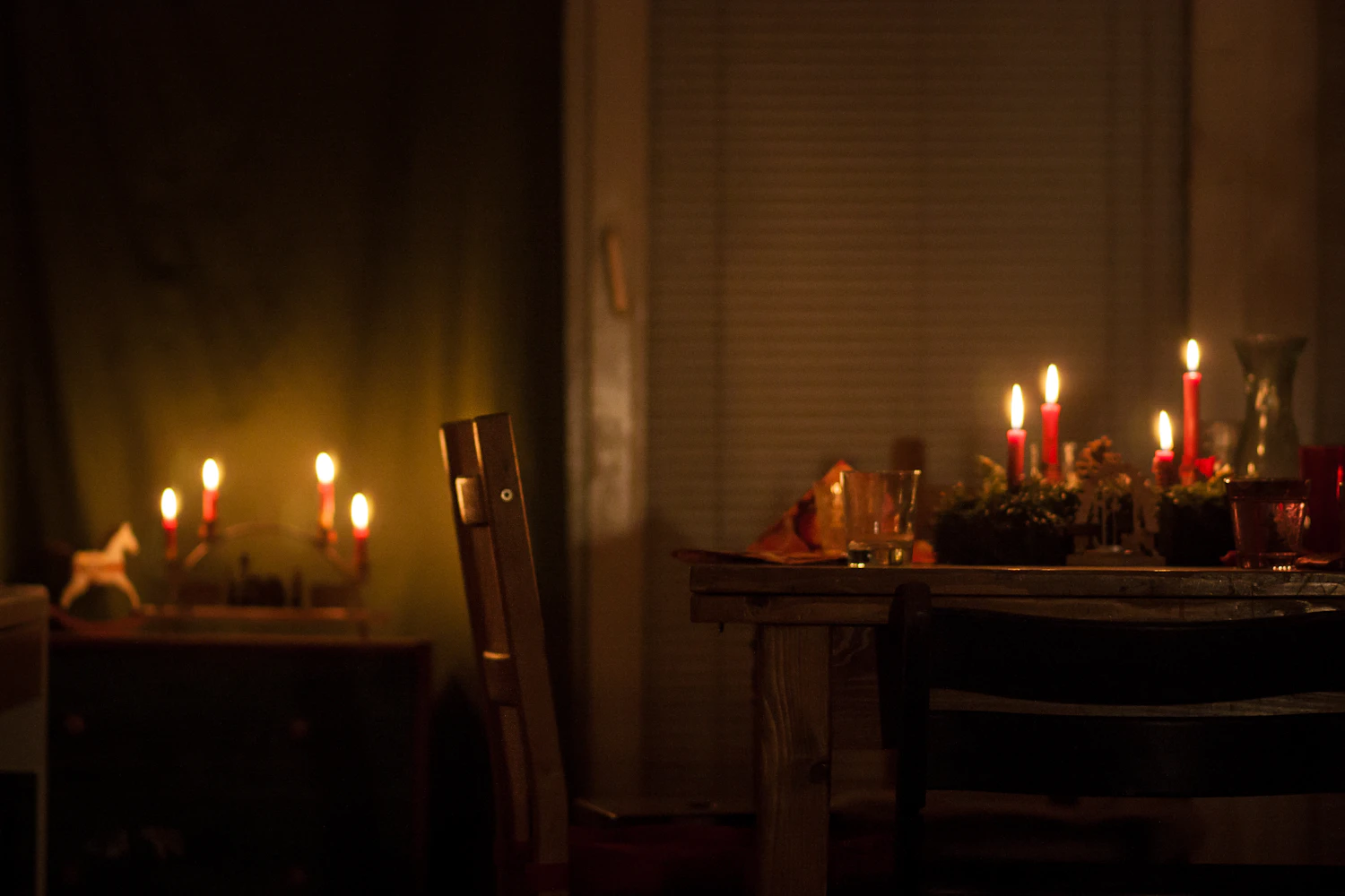 Candles burning along a table in a dim room with the lamps off