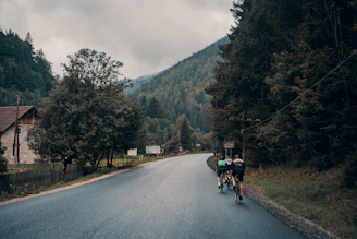 Group of triathletes cycling on a winding road through lush green Engadin countryside.