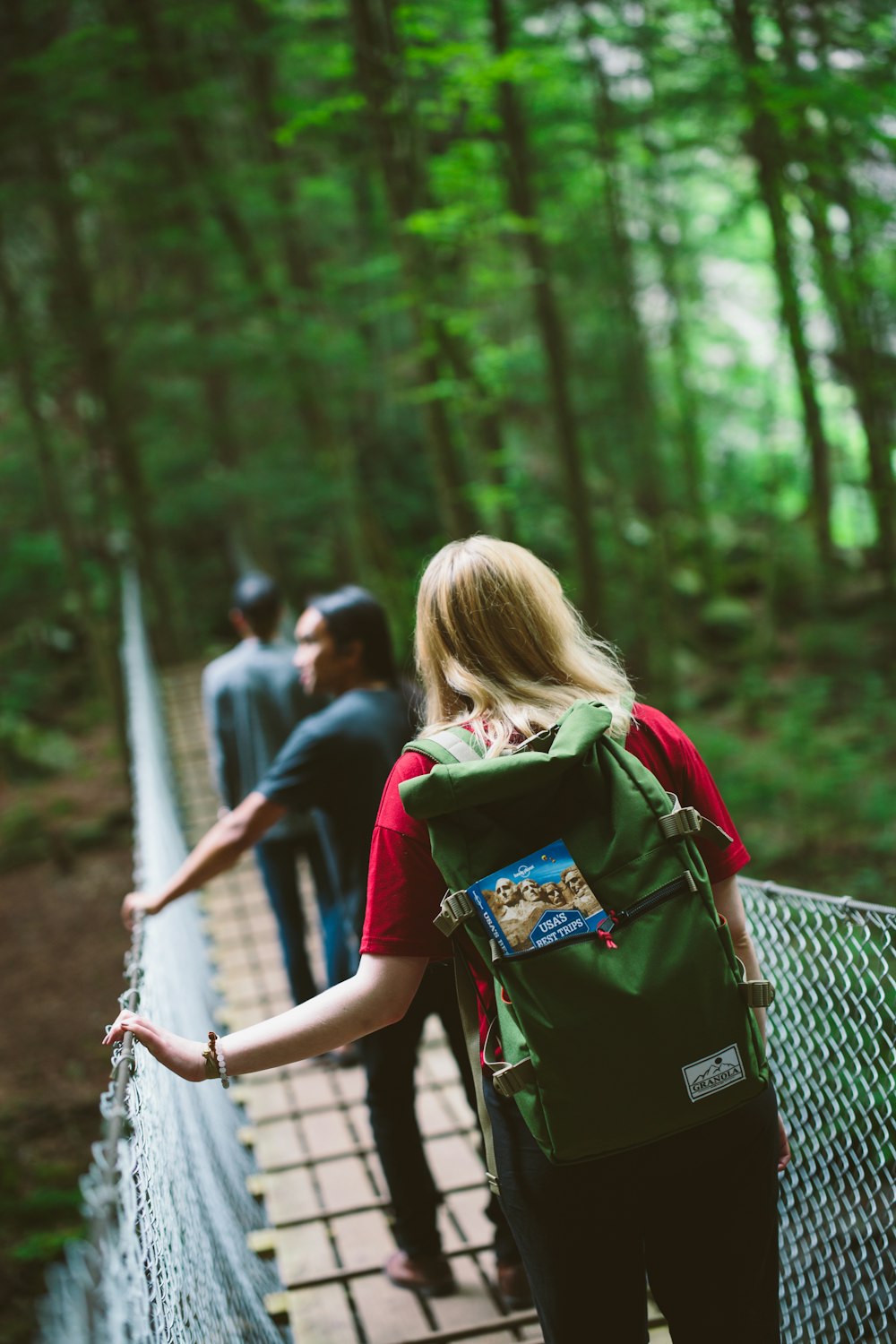 shallow depth of field photo of woman crossing hanging bridge