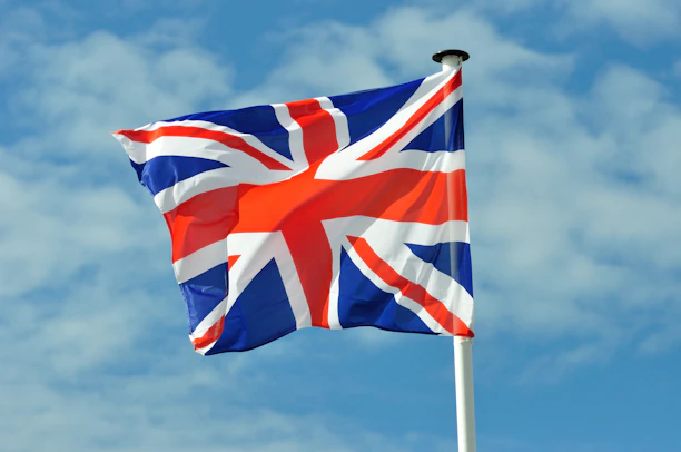 A vibrant Union Jack flag waving gently over a map of the United Kingdom filled with smiling families.