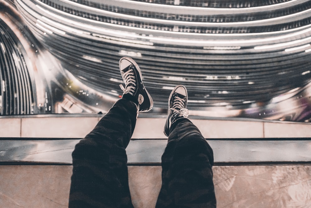 person taking photo of black Converse sneakers