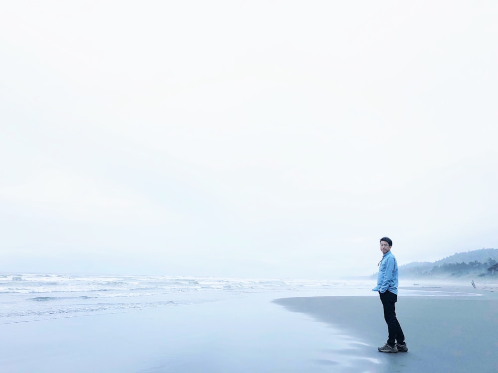 man standing at sea side during cloudy skies