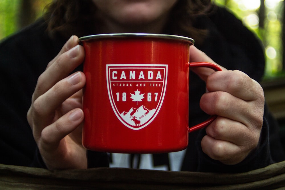 person holding red metal mug